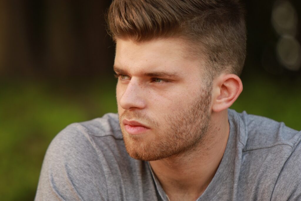 Blonder Mann in grauem T-Shirt mit Blick nach links