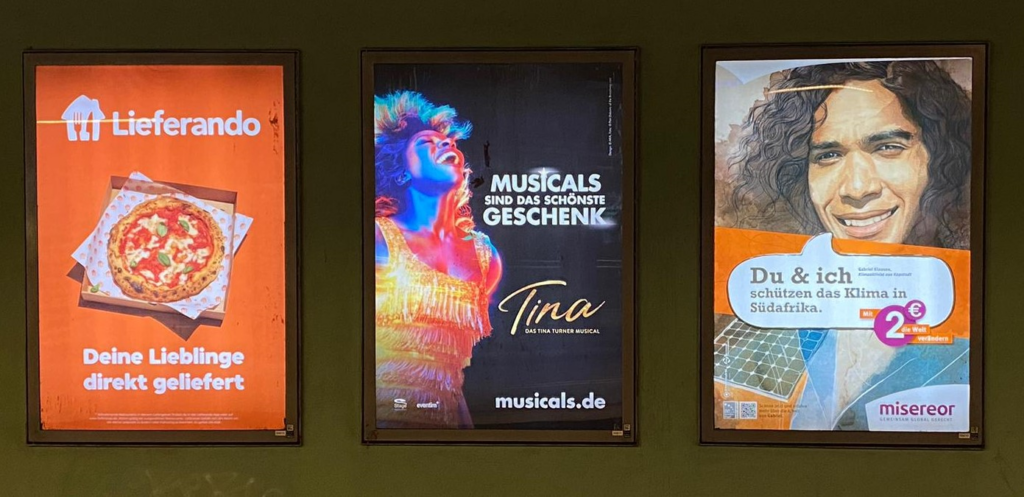 Aufnahme von drei verschiedenen bunten Werbeplakaten von Lieferando, Tina Turner Musical und misereor