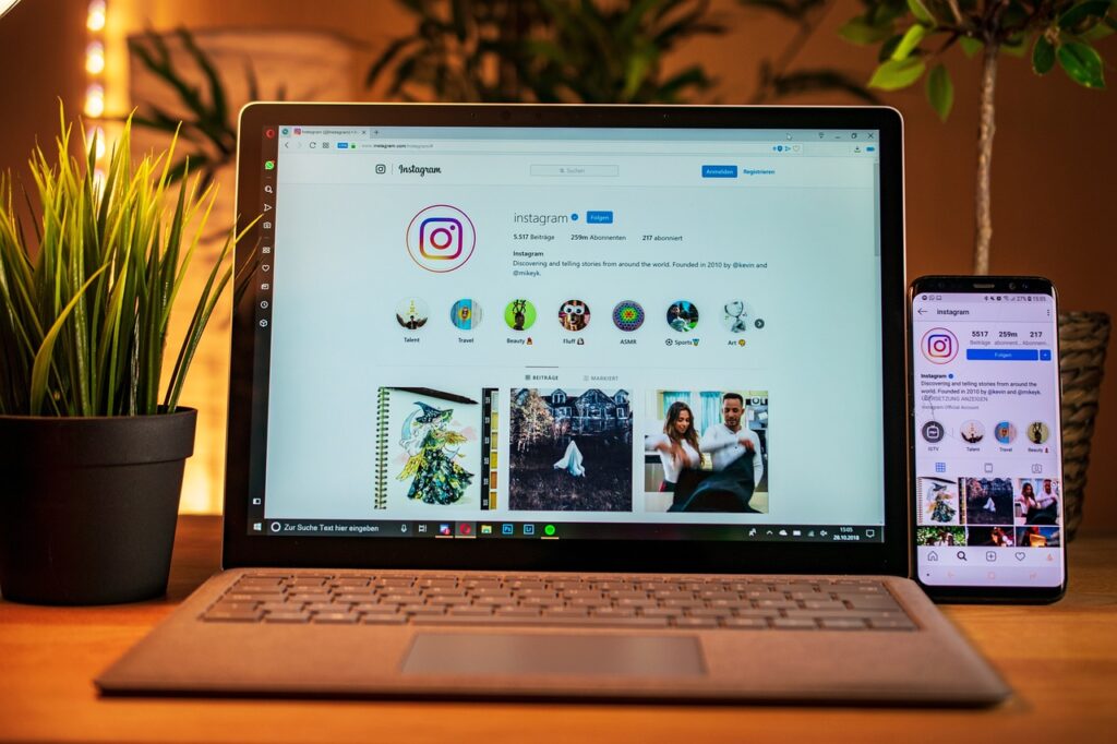Aufgeklappter Laptop mit der offiziellen Instagramseite von Instagram und daneben ein Handy mit dem gleichen Bildschirm.