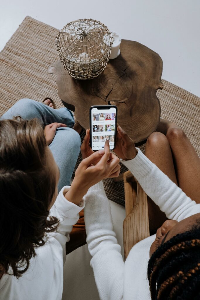 Zwei jungen Frauen schauen in ein Handydisplay mit geöffneter TikTok Suchseite.