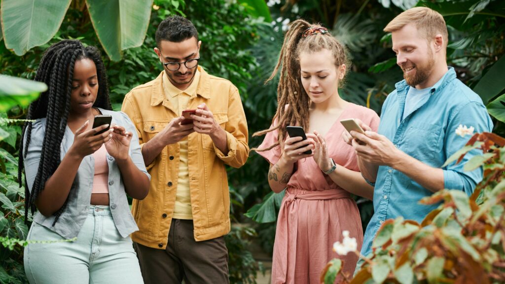 Vier Menschen nebeneinander, jede*r schaut auf das eigene Smartphone 
